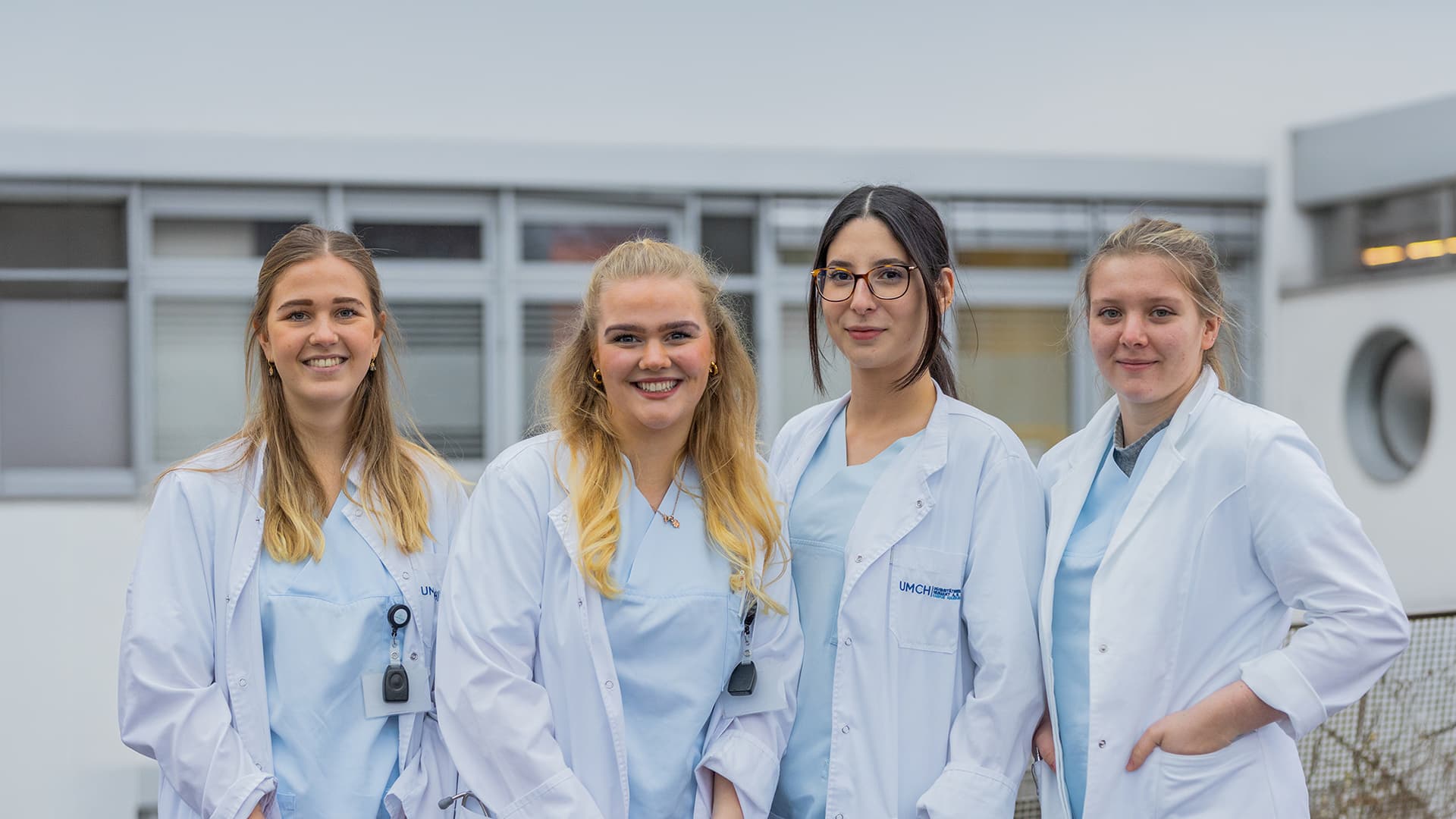 Four UMFST-UMCH medical students in lab coats on campus