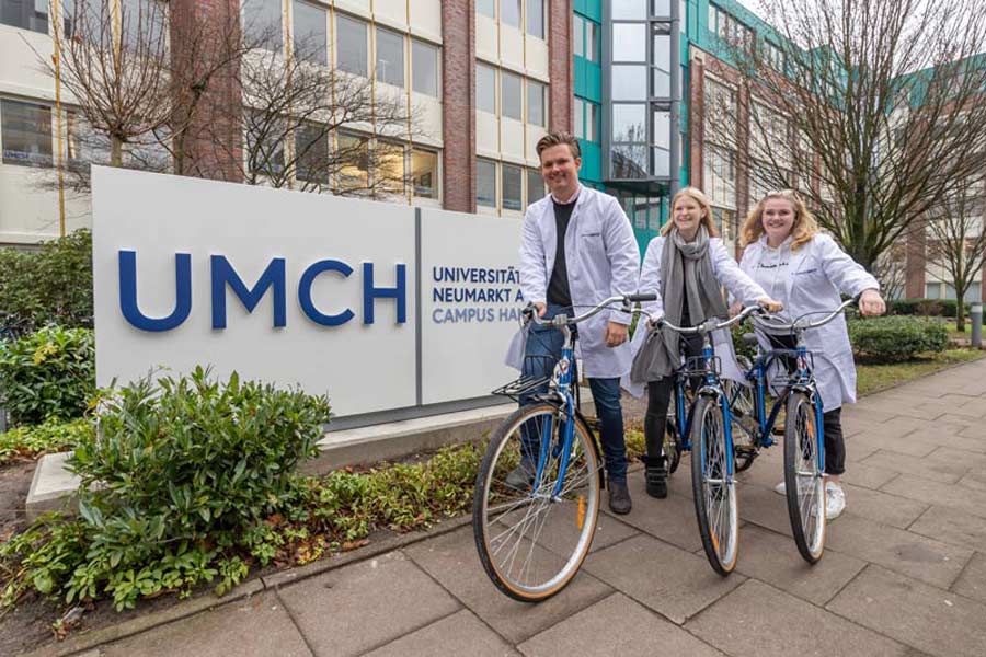 UMCH students in front of UMCH sign on on free UMCH / UMFST bikes
